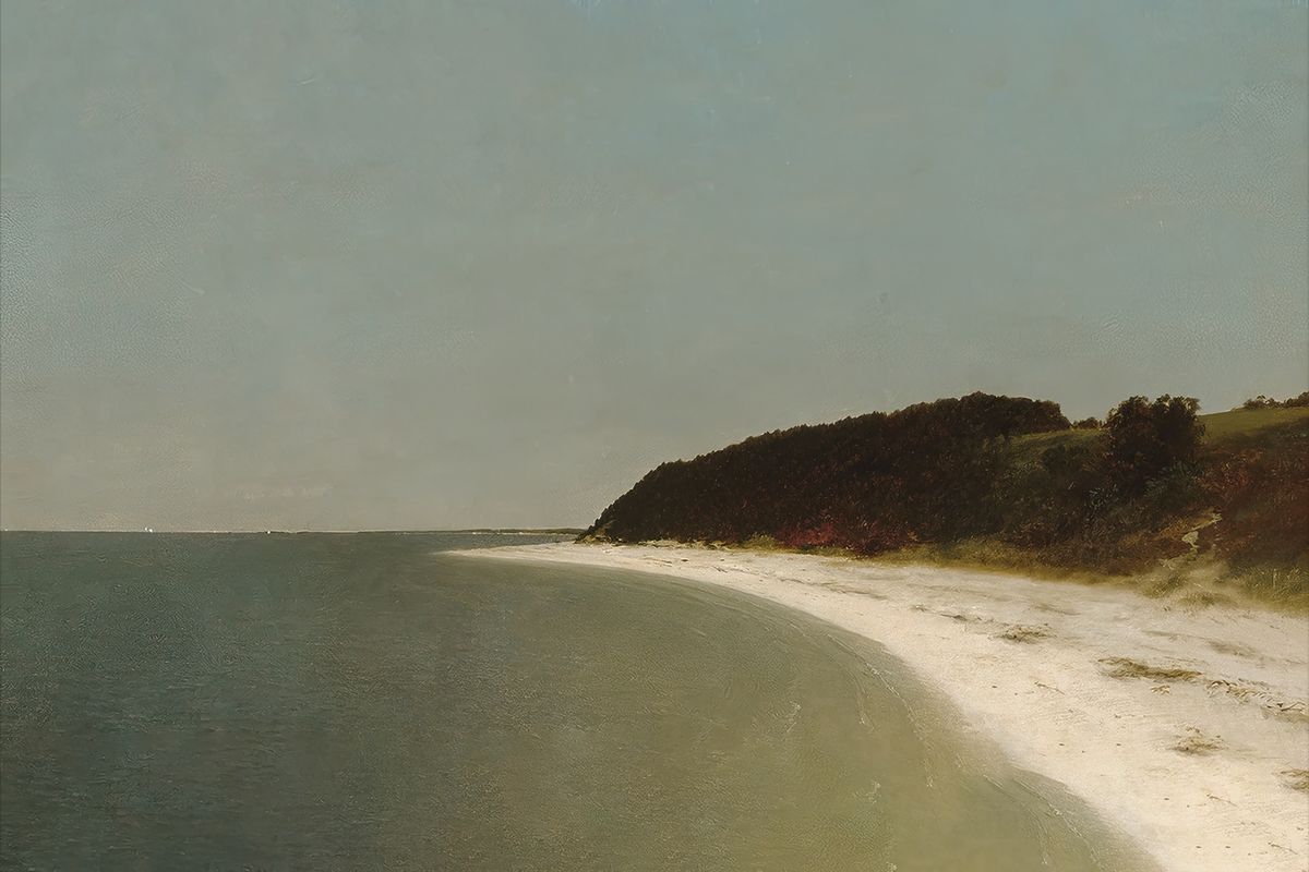 A curved sandy beach lined by a dark wooded cliff, with calm gray-green water on the left and a pale overcast sky above.