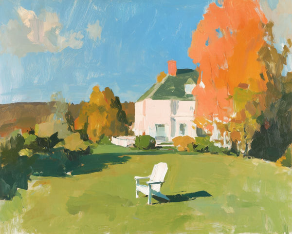 A white Adirondack chair on a green lawn in front of a white farmhouse surrounded by autumn trees under a blue sky.