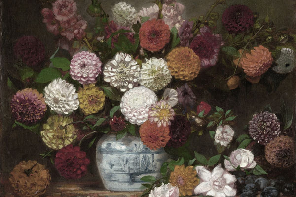 A large bouquet of mixed dahlias in a blue-and-white ginger jar on a dark ledge, with loose blooms and plums at the base.