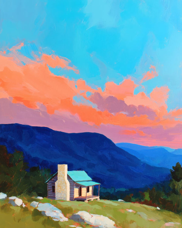 A lone log cabin with a stone chimney on a hillside below layered blue mountain ridges and a vivid orange and pink sunset sky